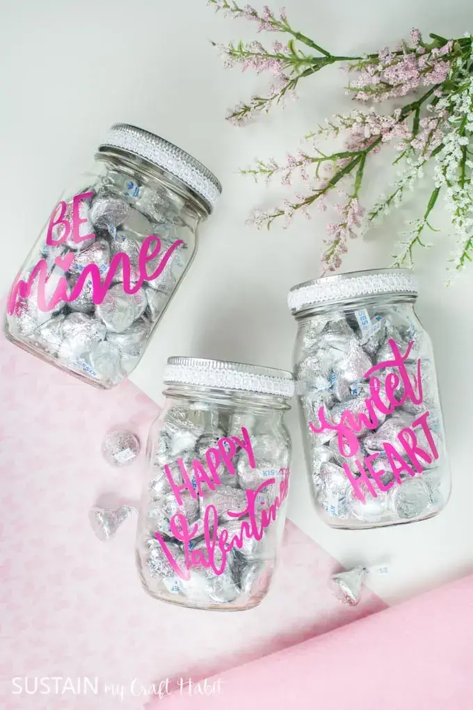 Cricut valentines day gift candy jars with silver candies inside.