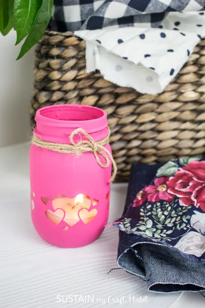Cricut mason jar candle holder painted pink with cut out heart image.