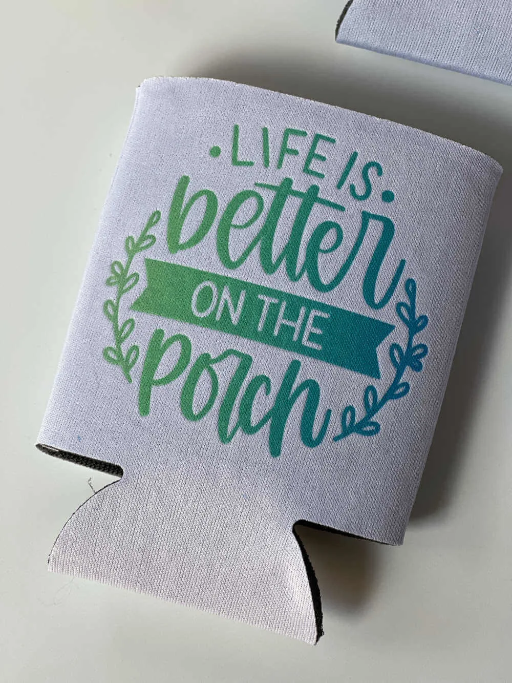Flattened can koozie with infusible ink design that says life is better on the porch.