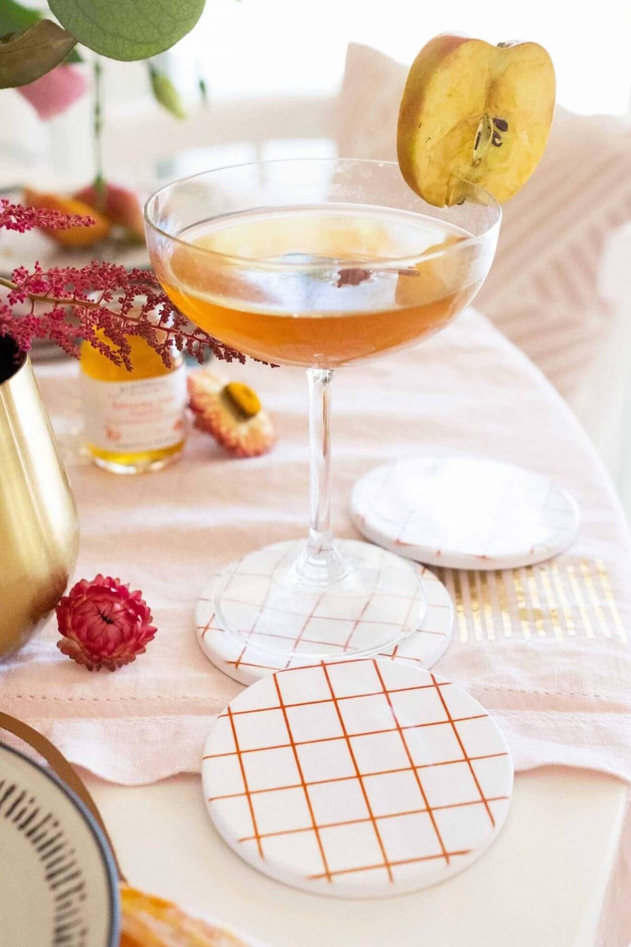 Checkered infusible ink coasters with cocktail on decorated table.