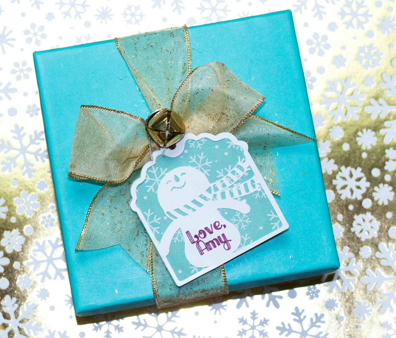 Cute snowman gift tag tied on gift with ribbon.