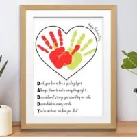 free printable father's day handprint art template in wooden frame on shelf with pot plants.