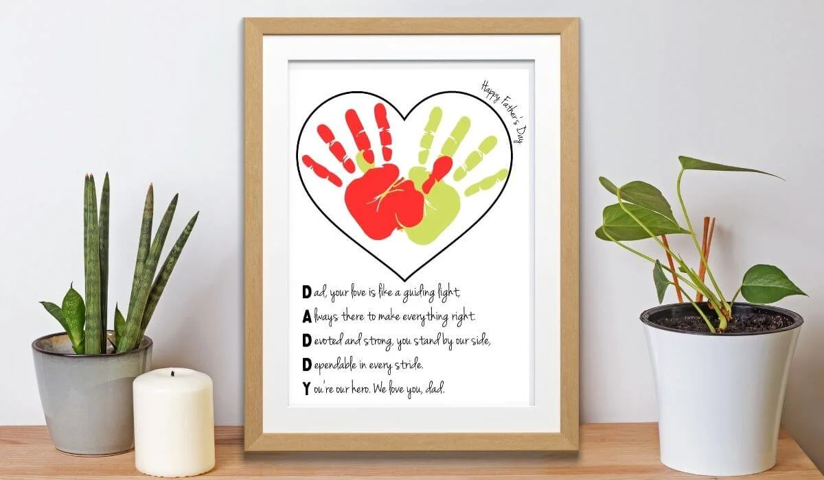 Free printable father's day handprint art template in wooden frame on shelf with pot plants.