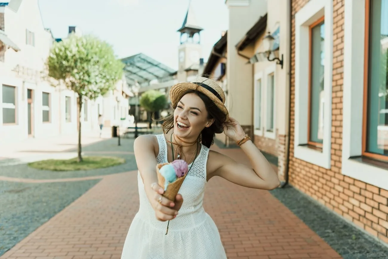 Happy woman holding an ice cream while walking down the street.
